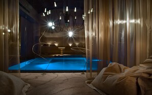 A dimly lit room with a blue carpet, a chandelier, and curtains.