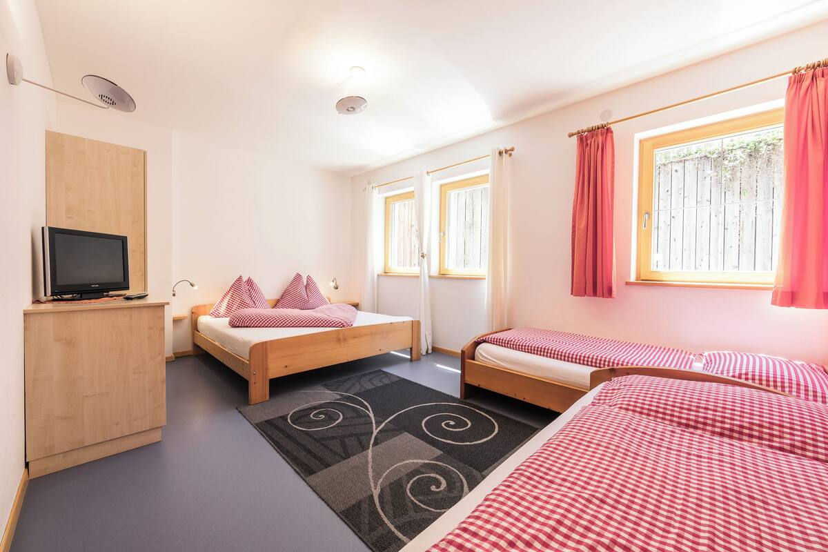 A bedroom with two beds, a TV, and a wooden cabinet.