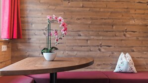 A round wooden table with a potted orchid plant. - Hotel Apartment Haus Gitschberg (Vandoies)