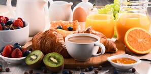 A breakfast setting with croissants, coffee, fruits, and a glass of orange juice. - Hotel Apartment Haus Gitschberg (Vandoies)