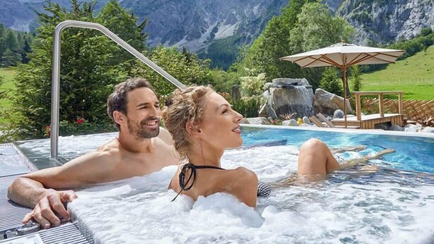 A couple in a hot tub with a mountainous landscape in the background. - Hotel Apartment Haus Gitschberg (Vandoies)