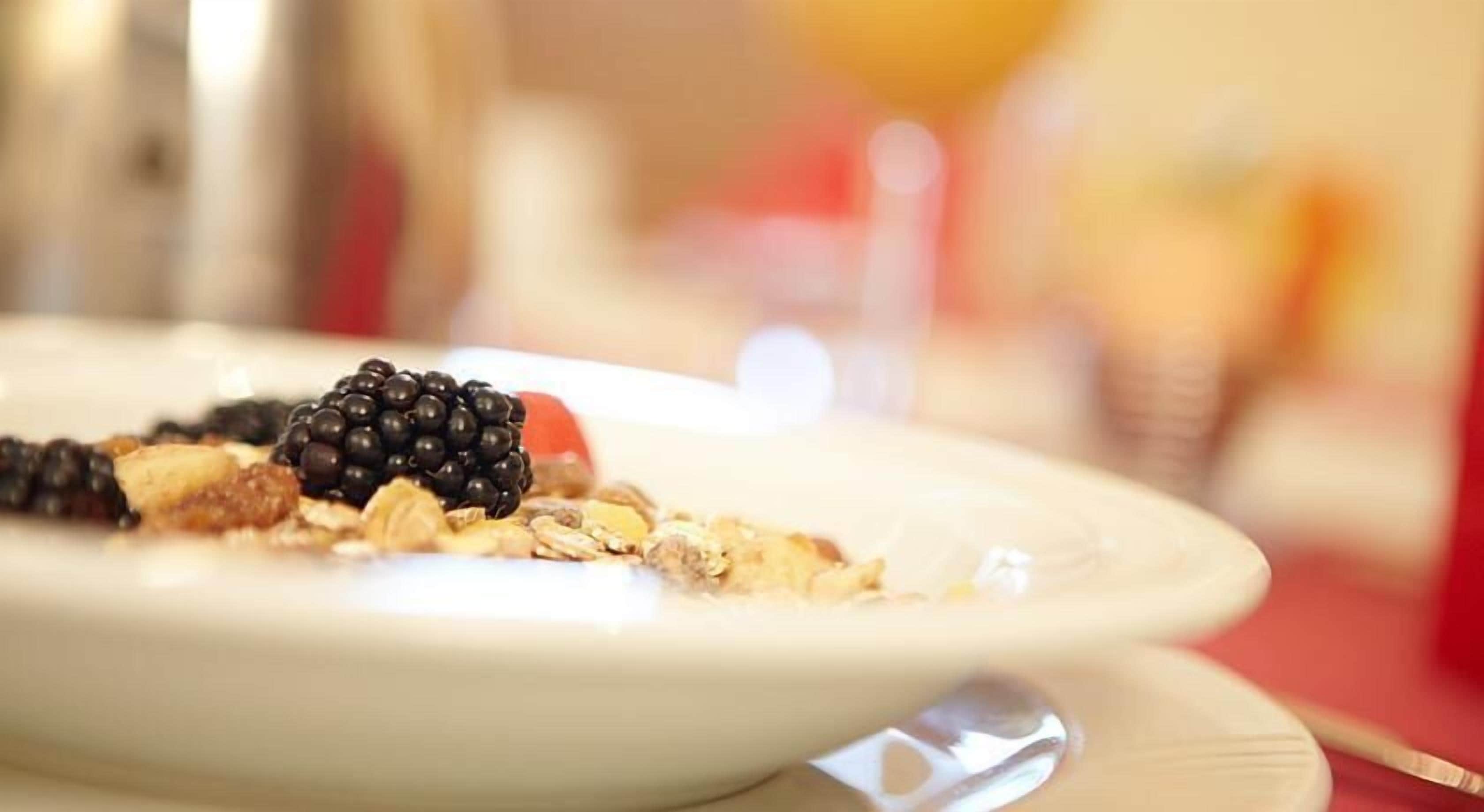 Ein Teller mit Kuchenstück, belegt mit Brombeeren und Nüssen.