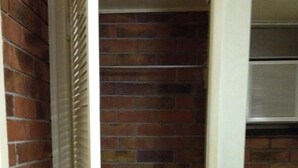 Un estrecho pasillo de ladrillo con una puerta blanca a la izquierda y una pared blanca a la derecha.