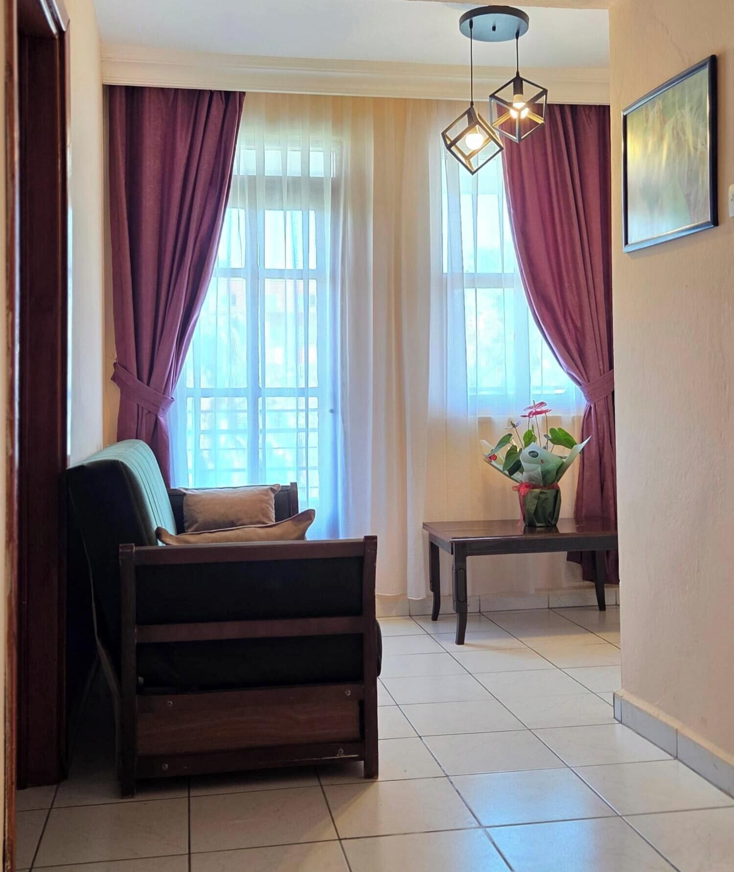 A room with a sofa, a table with a vase, and a hanging light fixture.