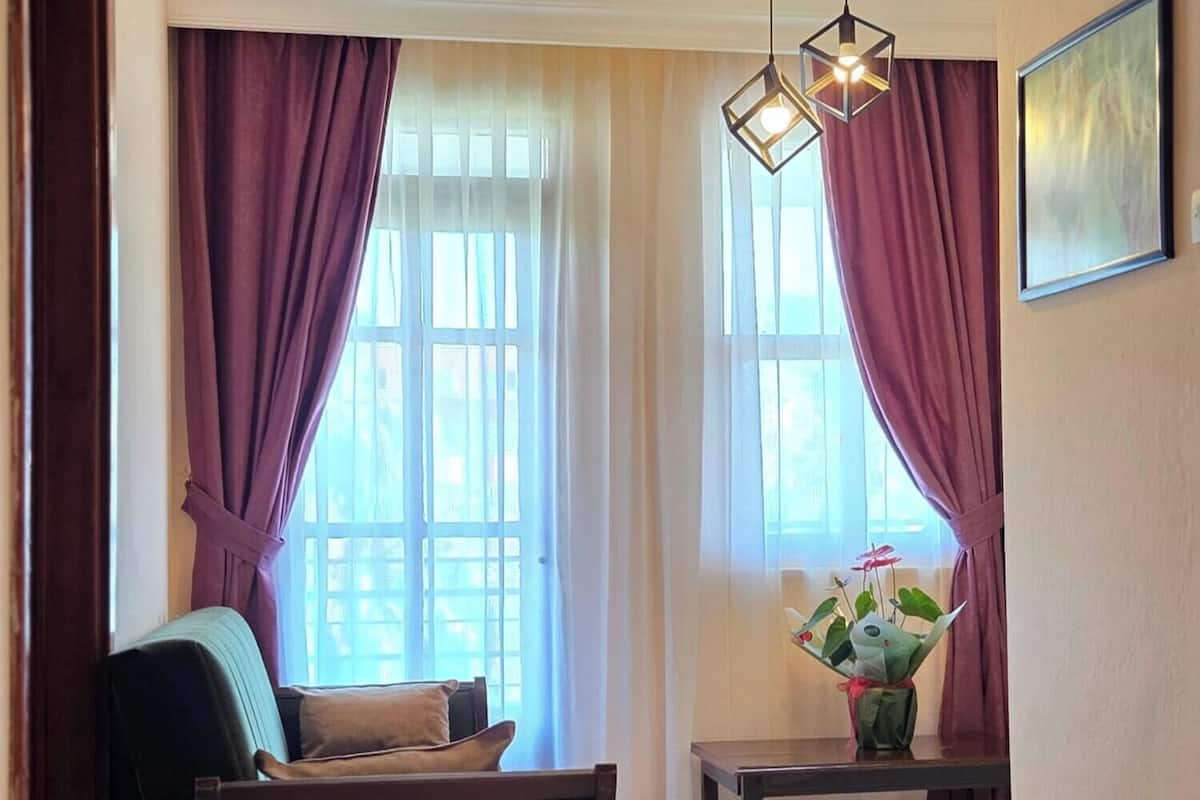 A room with a sofa, a table with a vase, and a hanging light fixture.