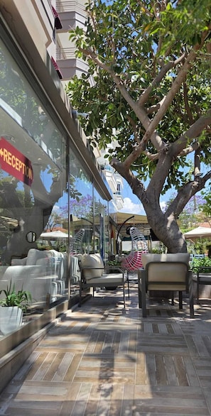 A reception area with a sign, outdoor seating, and a tree.