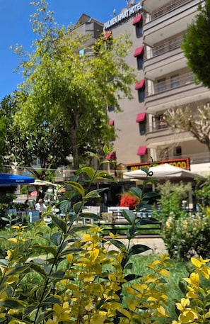 A hotel with balconies, outdoor seating, and greenery.