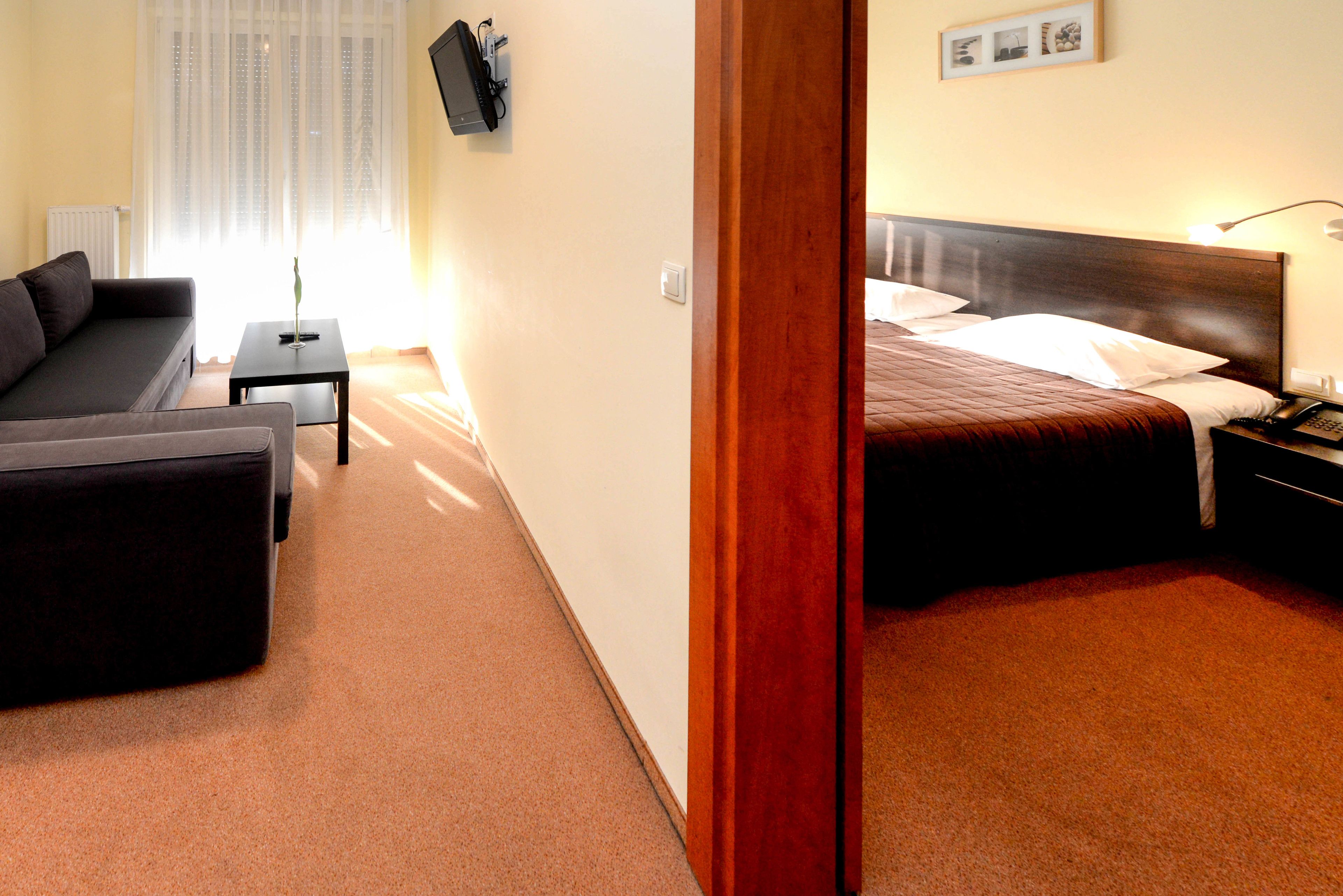 Una habitación de hotel con cama, sofá, una mesita y una mesilla de noche.