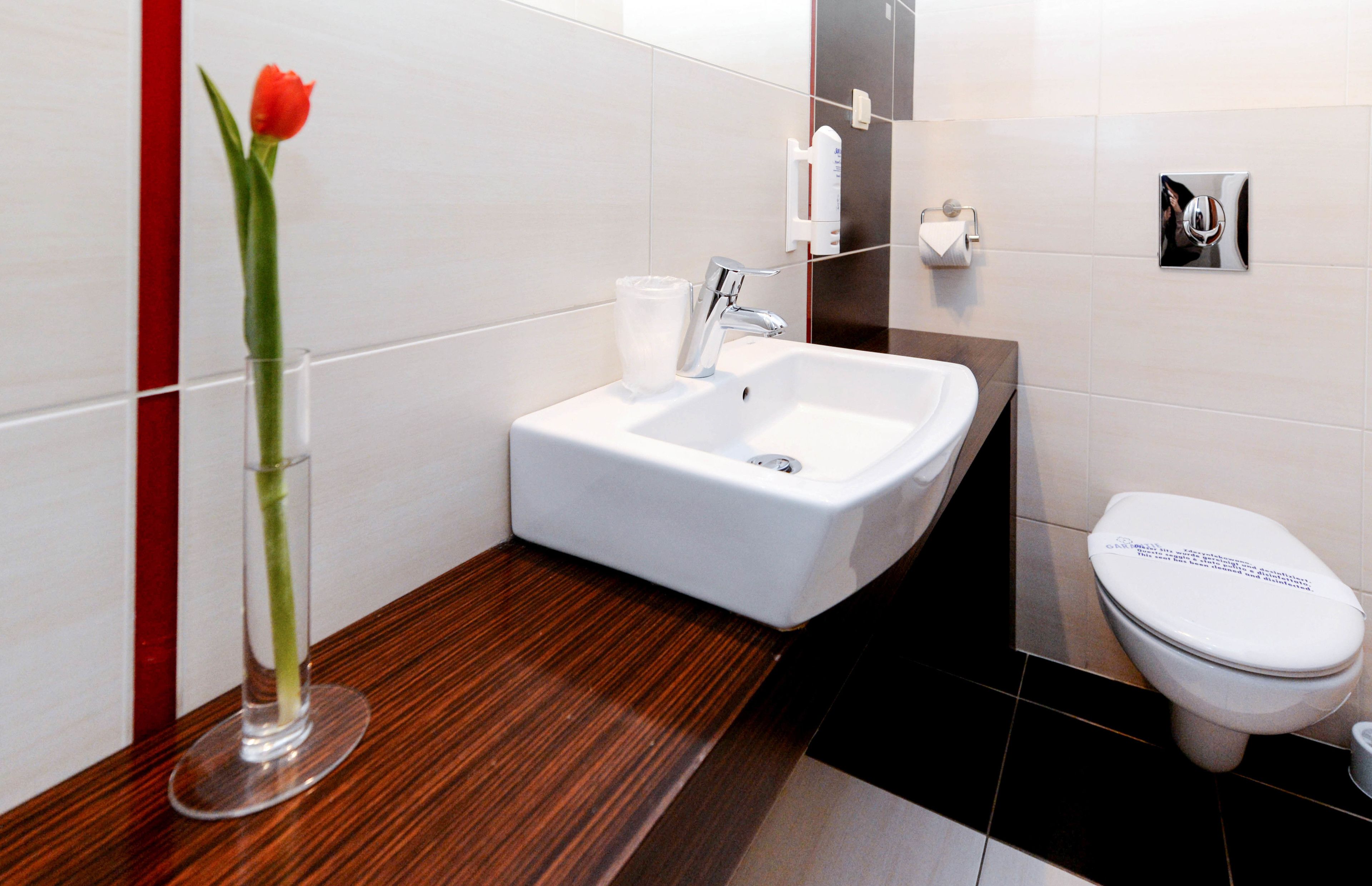 Un baño moderno con un lavamanos blanco, un inodoro y una pared de acento roja.