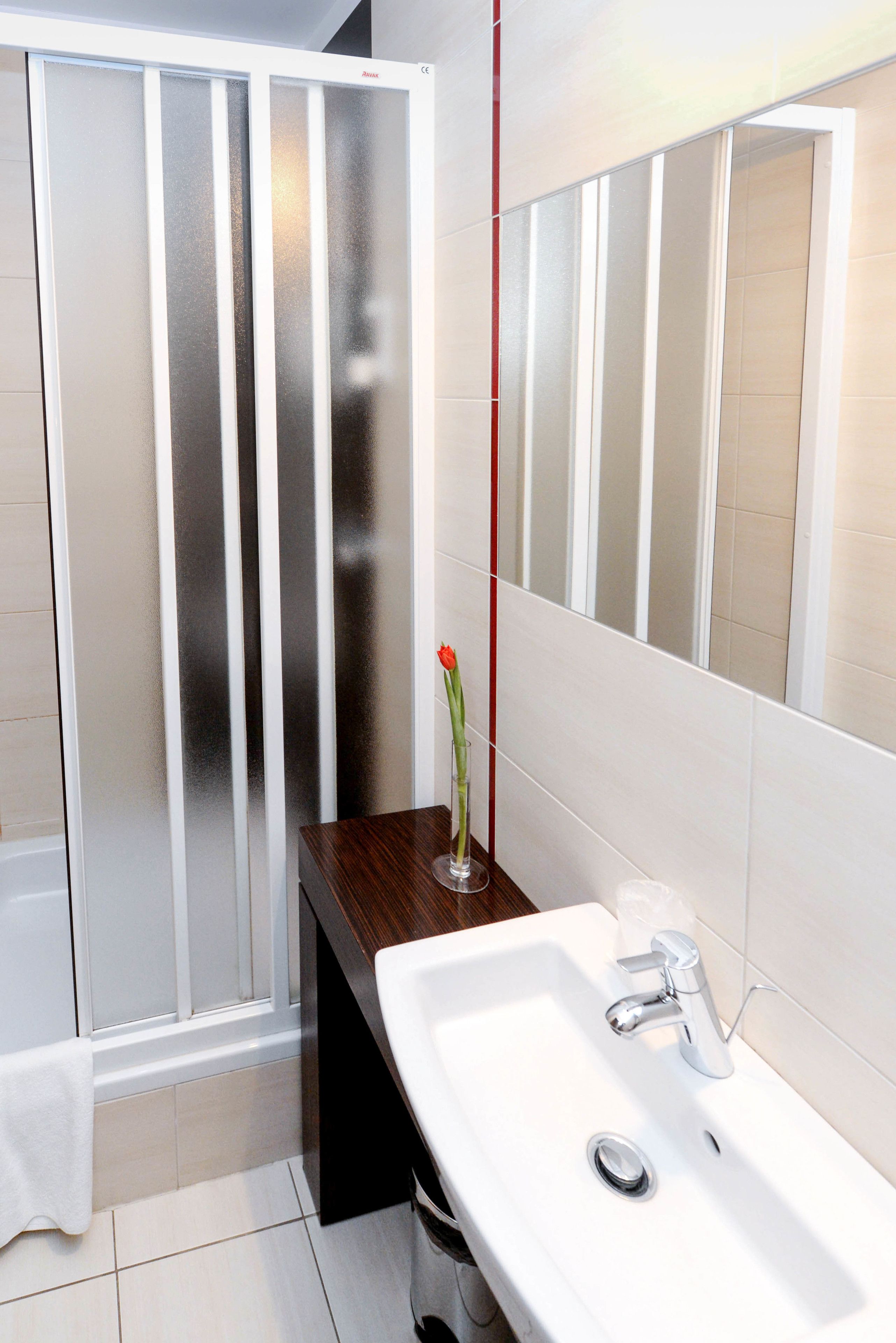 Un baño moderno con un lavabo blanco, un espejo y una cabina de ducha con vidrio esmerilado.