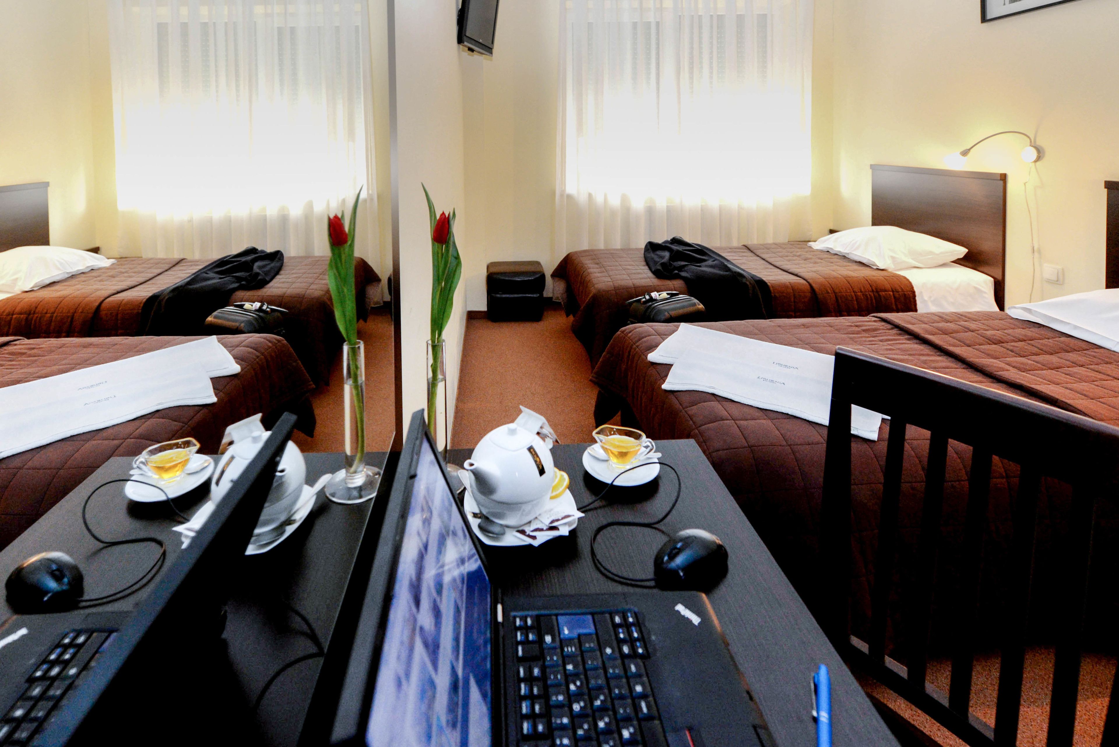 A hotel room with two beds, a desk with a computer, and a coffee table.