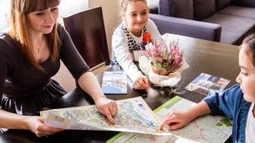 A family of three at a dining table with a map and a potted plant.