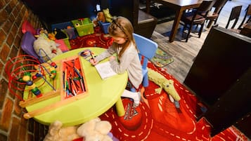 A child at a table with toys and drawing materials.