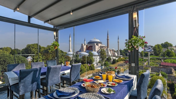 Un comedor con una mesa dispuesta para cuatro personas, con vistas a una mezquita con múltiples cúpulas y minaretes.