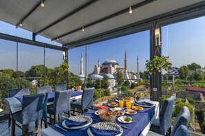 Un comedor con una mesa dispuesta para cuatro personas, con vistas a una mezquita con múltiples cúpulas y minaretes.