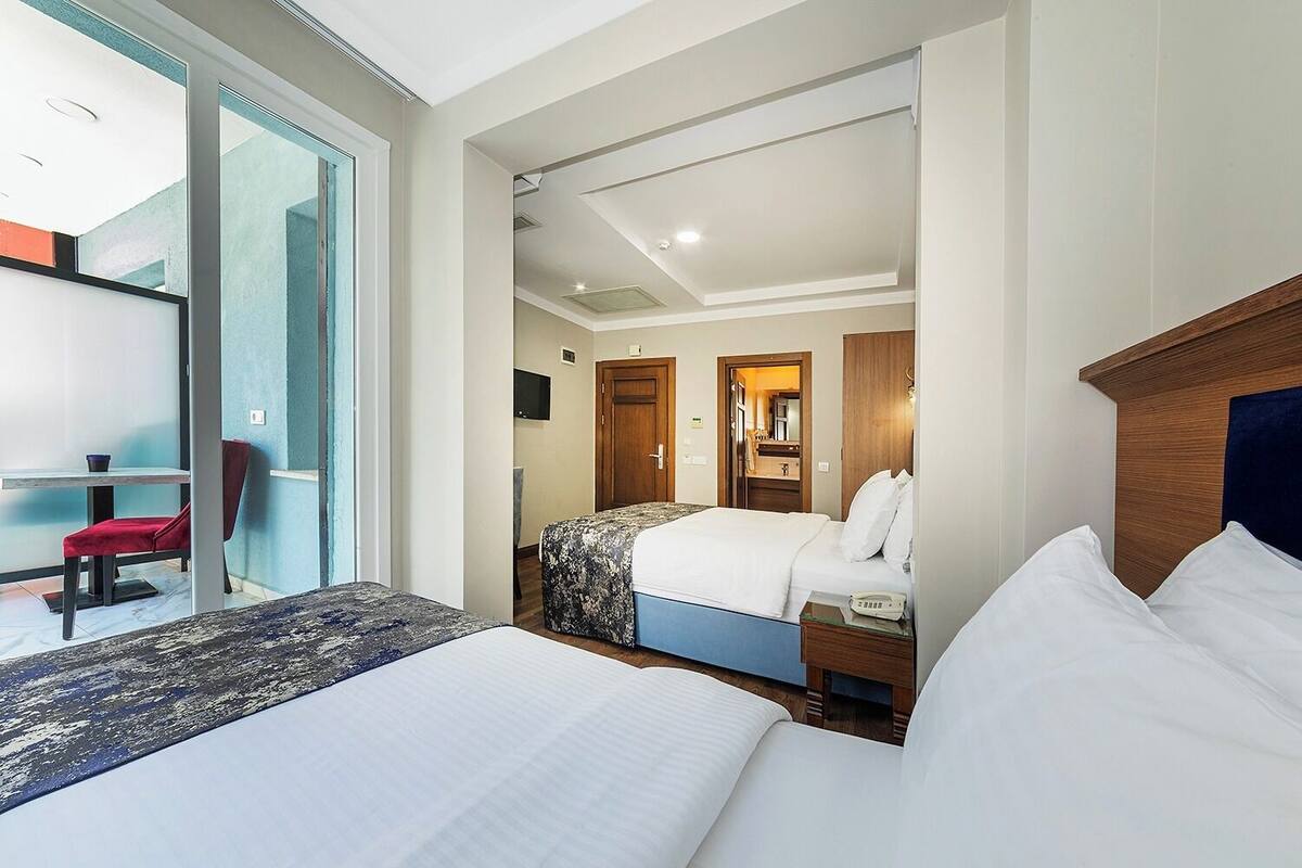 Une chambre d’hôtel avec deux lits, un bureau et une chaise.