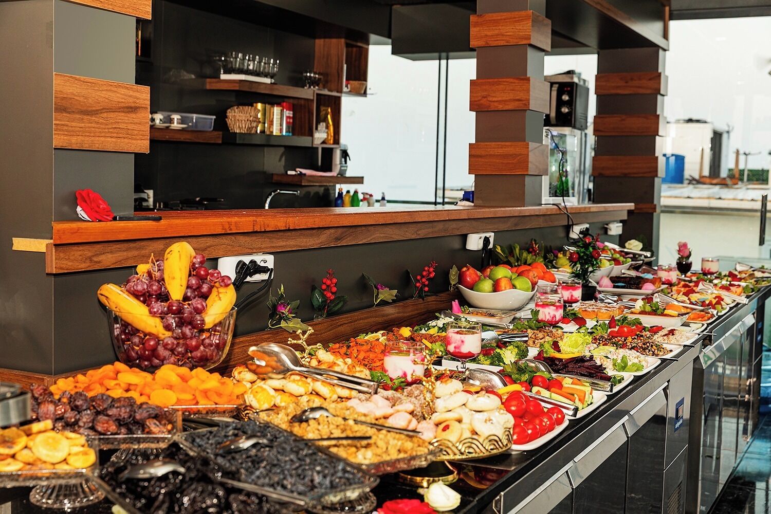 A buffet with a variety of food items including fruits, vegetables, and desserts.