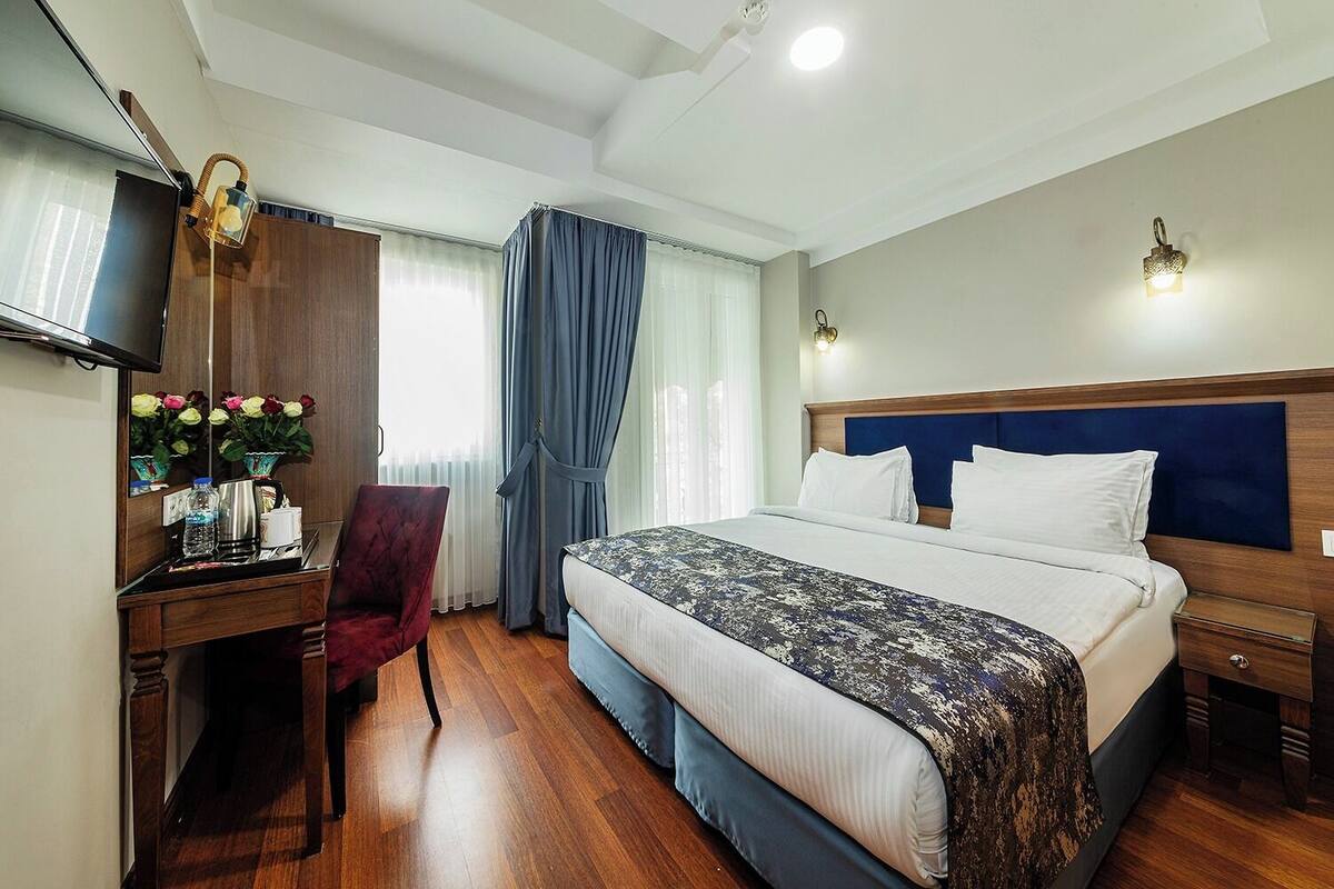 Une chambre d’hôtel avec un grand lit, un bureau avec une chaise, une télévision et un miroir.