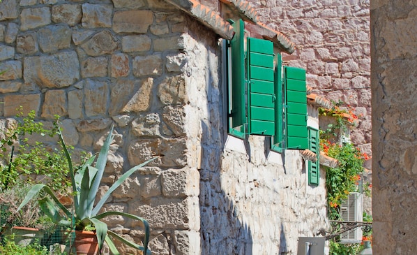 A stone building with green shutters and a potted plant.