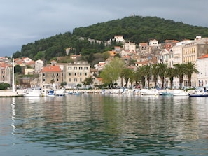 A coastal town with a marina, historic buildings, and a hill in the background.