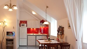 Cozinha compacta com armários brancos, micro-ondas e área de refeições com mesa e cadeiras.