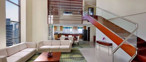 A modern living room with a sofa, coffee table, and a staircase with glass railings.