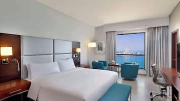 Habitación de hotel con una cama grande, un escritorio, una silla, una mesita y vistas a una noria y al agua.