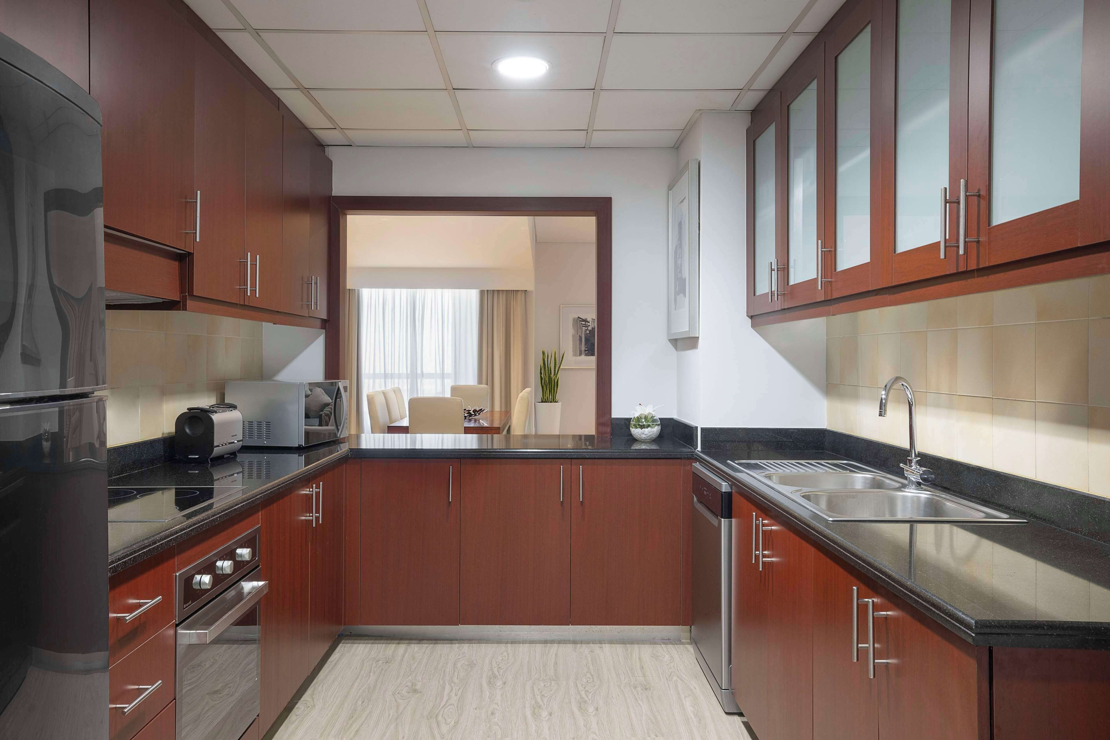 Una cocina moderna con gabinetes de madera, electrodomésticos de acero inoxidable y encimera negra.