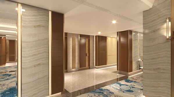 A modern hotel corridor with marble walls, a patterned carpet, and a well-lit ceiling.
