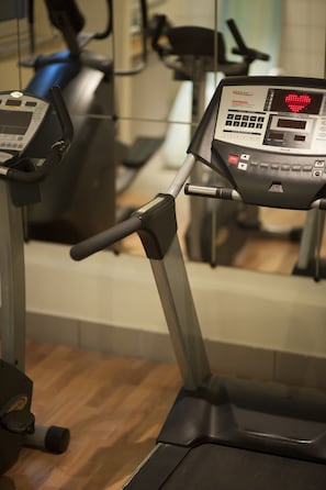 A treadmill with a digital display and control panel, in a gym setting with other exercise equipment in the background. - Wyndham Stuttgart Airport Messe (Leinfelden-Echterdingen)