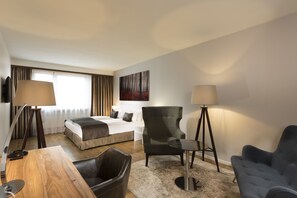 Une chambre d’hôtel avec un lit, un bureau, une chaise, une lampe et un tableau au mur.