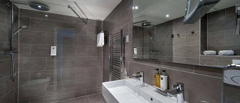 Un baño moderno con un lavabo grande, zona de ducha y espejo.