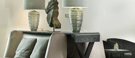 Una sala de estar moderna con un sofá, dos lámparas con bases texturizadas y una escultura decorativa.