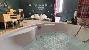 Ein Zimmer mit einer großen Badewanne voller Wasser, einem Bett mit Kissen, einem Schreibtisch mit Lampe und einer Wand mit motivierenden Schriftzügen.