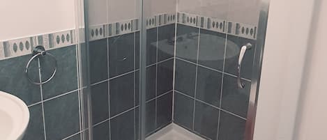 Eine Duschkabine mit Glaswänden, einer Handbrause und einem wandmontierten Wasserhahn.