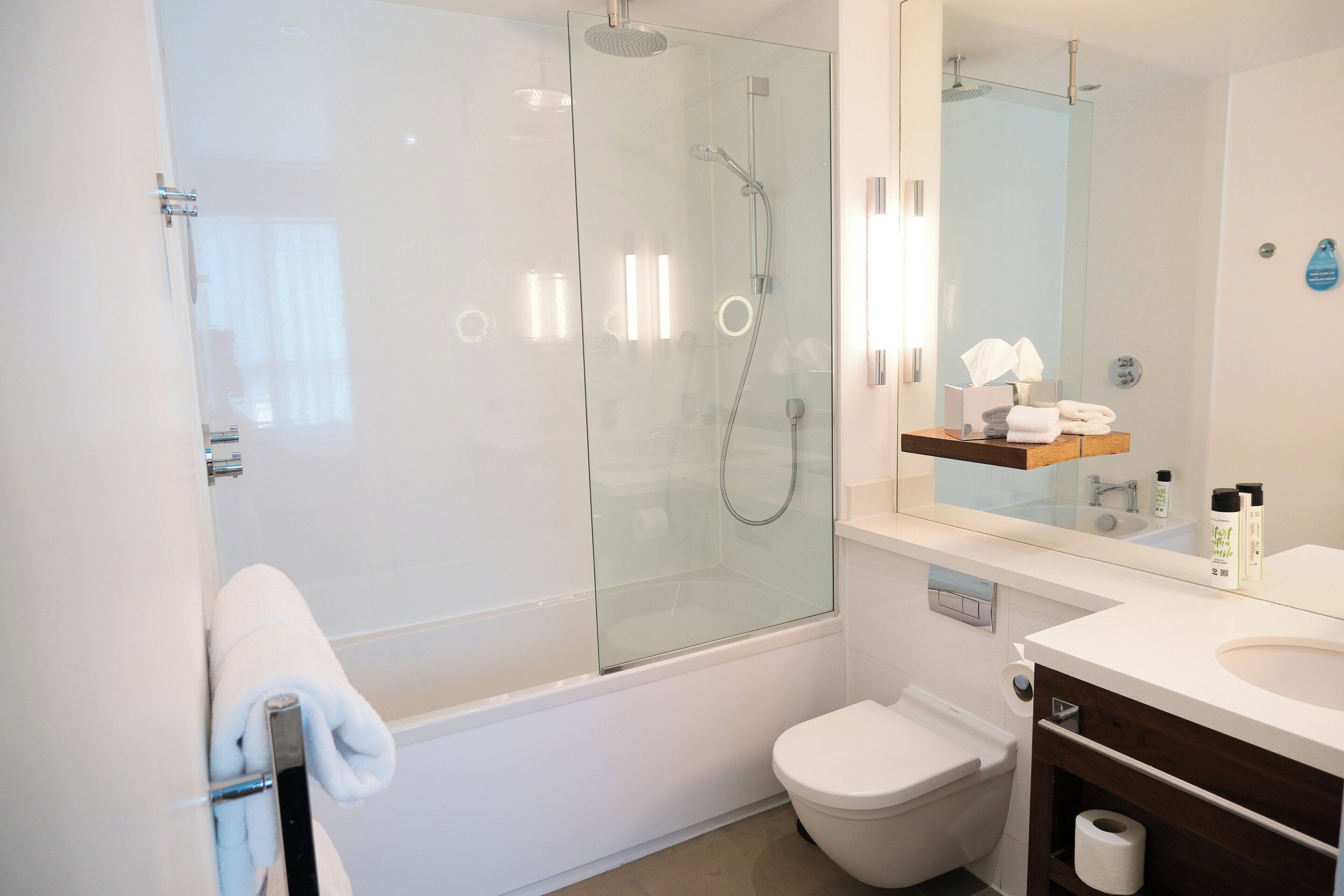 Un baño moderno con cabina de ducha de vidrio, inodoro y tocador con espejo.
