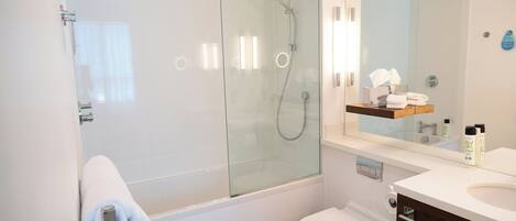 Un baño moderno con cabina de ducha de vidrio, inodoro y tocador con espejo.