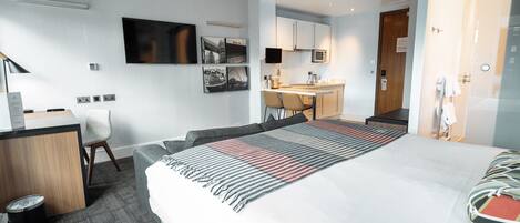 Une chambre d’hôtel moderne équipée d’un lit, d’un bureau et d’une kitchenette.