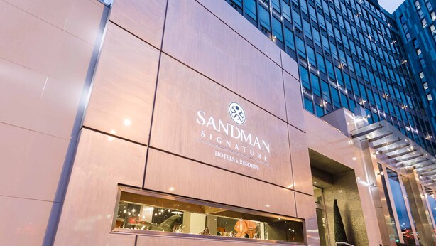 A modern building with a prominent sign for 'Sandman Signature Hotels & Resorts'.