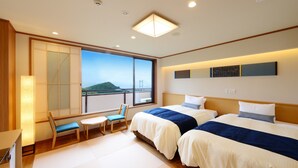 A hotel room with two beds, a desk, a chair, and a large window offering a view of a bridge and hills. - WASHU BULE RESORT Kasago (Kurashiki)