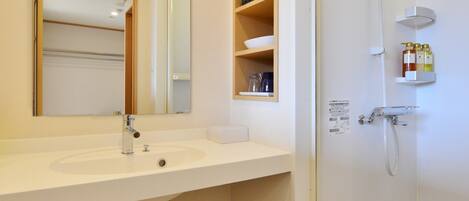 A modern bathroom with a white sink, mirror, and shower.