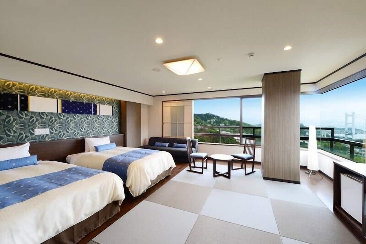 A hotel room with two beds, a seating area, and a large window with a view.