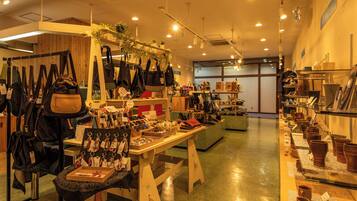 Een winkel met handtassen, sieraden en keramiek, tentoongesteld op tafels en planken.