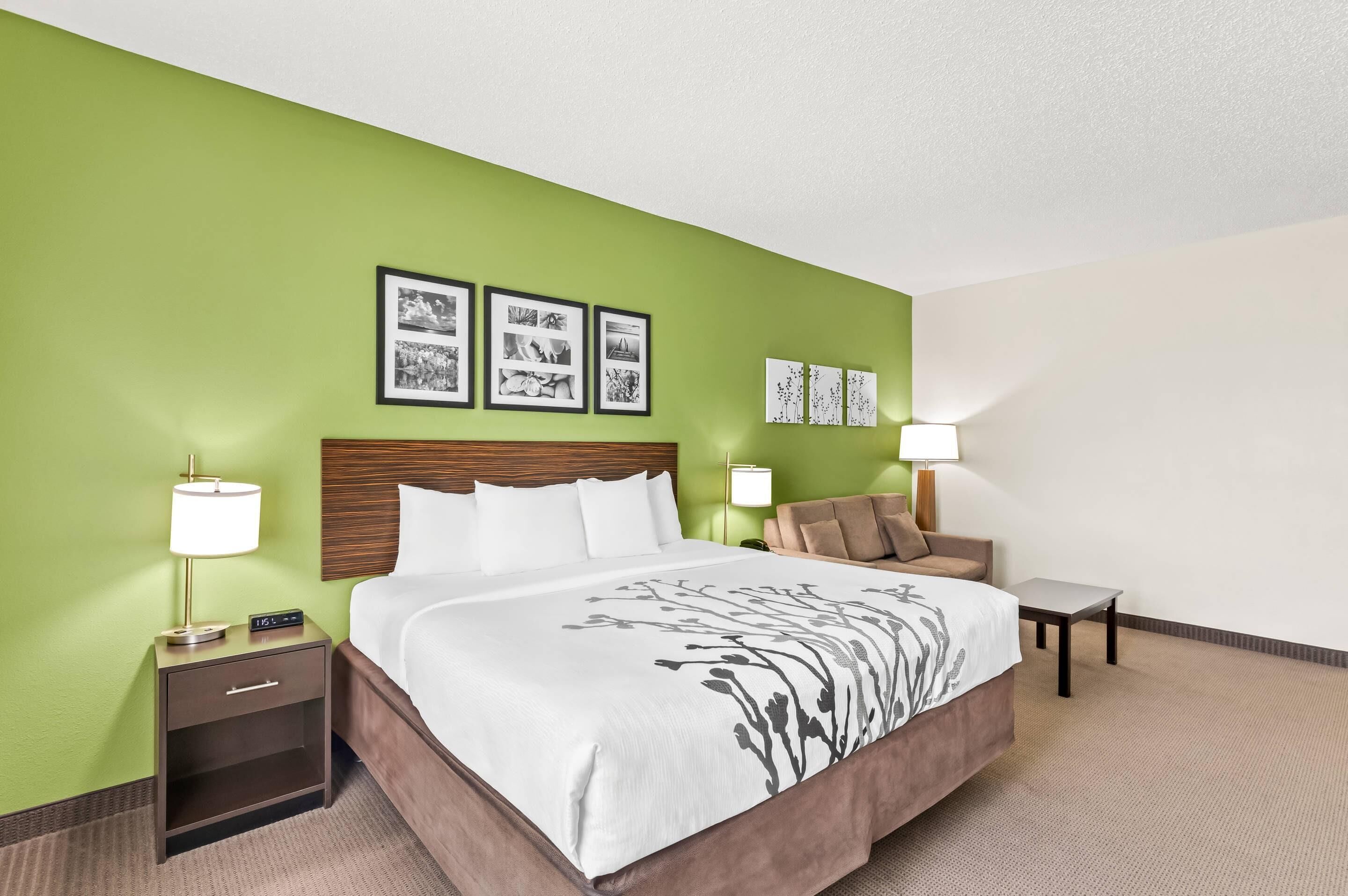 A hotel room with a large bed, two bedside tables, a chair, and wall-mounted artwork.