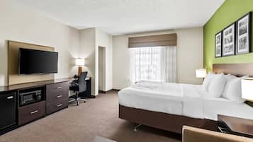 Una habitación de hotel con cama, escritorio, televisor y microondas.