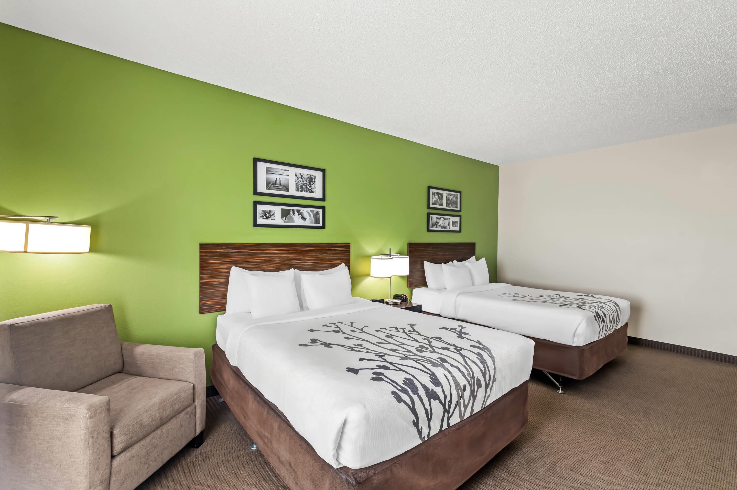 A hotel room with two beds, a sofa, and a nightstand with lamps.