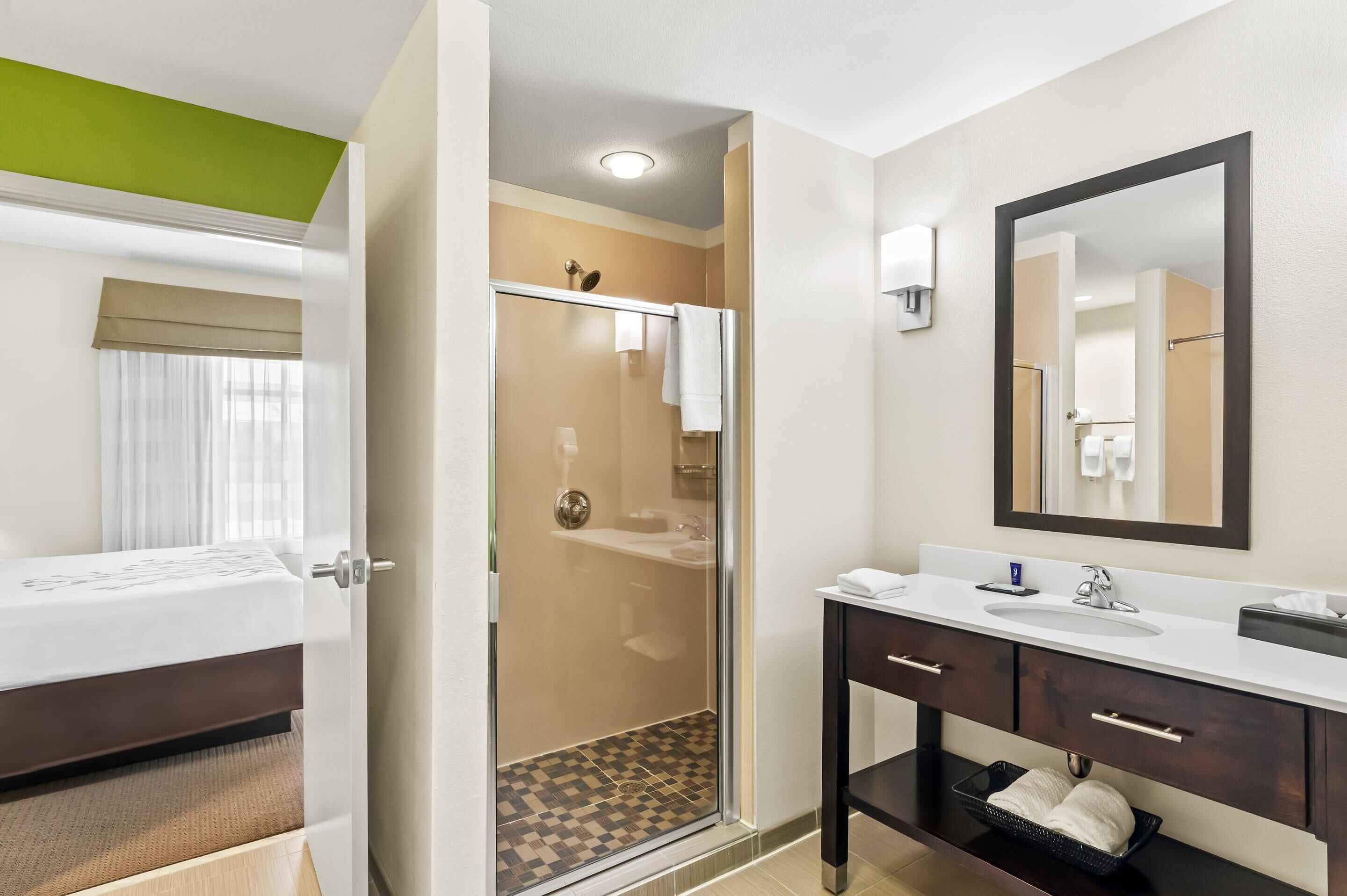 A hotel bathroom with a shower, a sink, and a mirror.