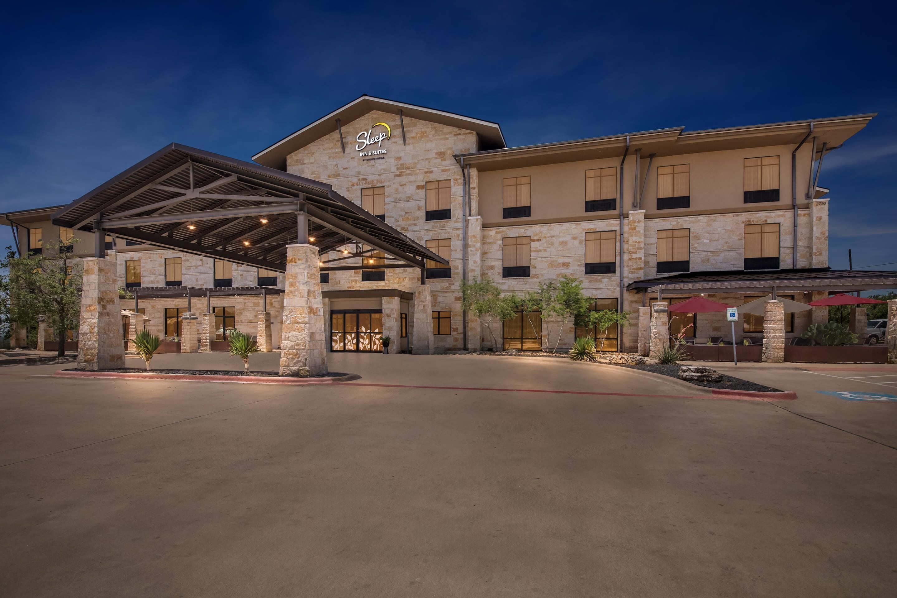 A hotel with a stone facade, a covered entrance, and a parking lot.