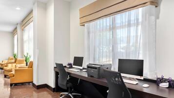 A modern office space with a long desk, multiple chairs, and two computer monitors.