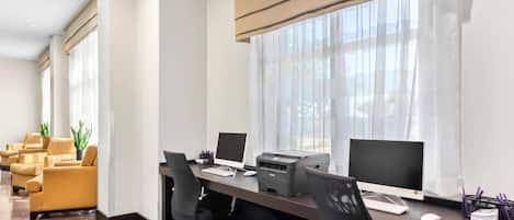 A modern office space with a long desk, multiple chairs, and two computer monitors.